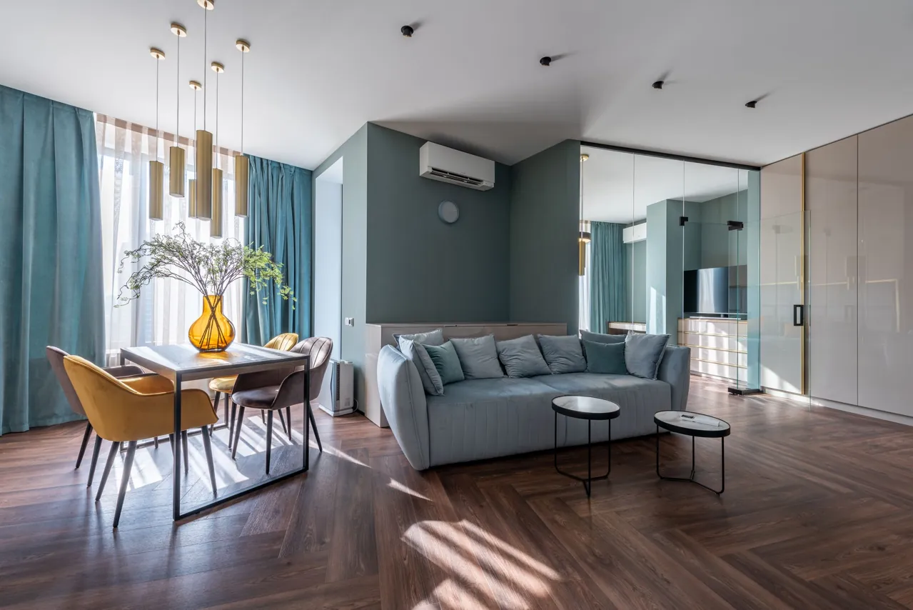 Modern blue sofa, round coffee tables, and upholstered dining chairs in a light-filled interior